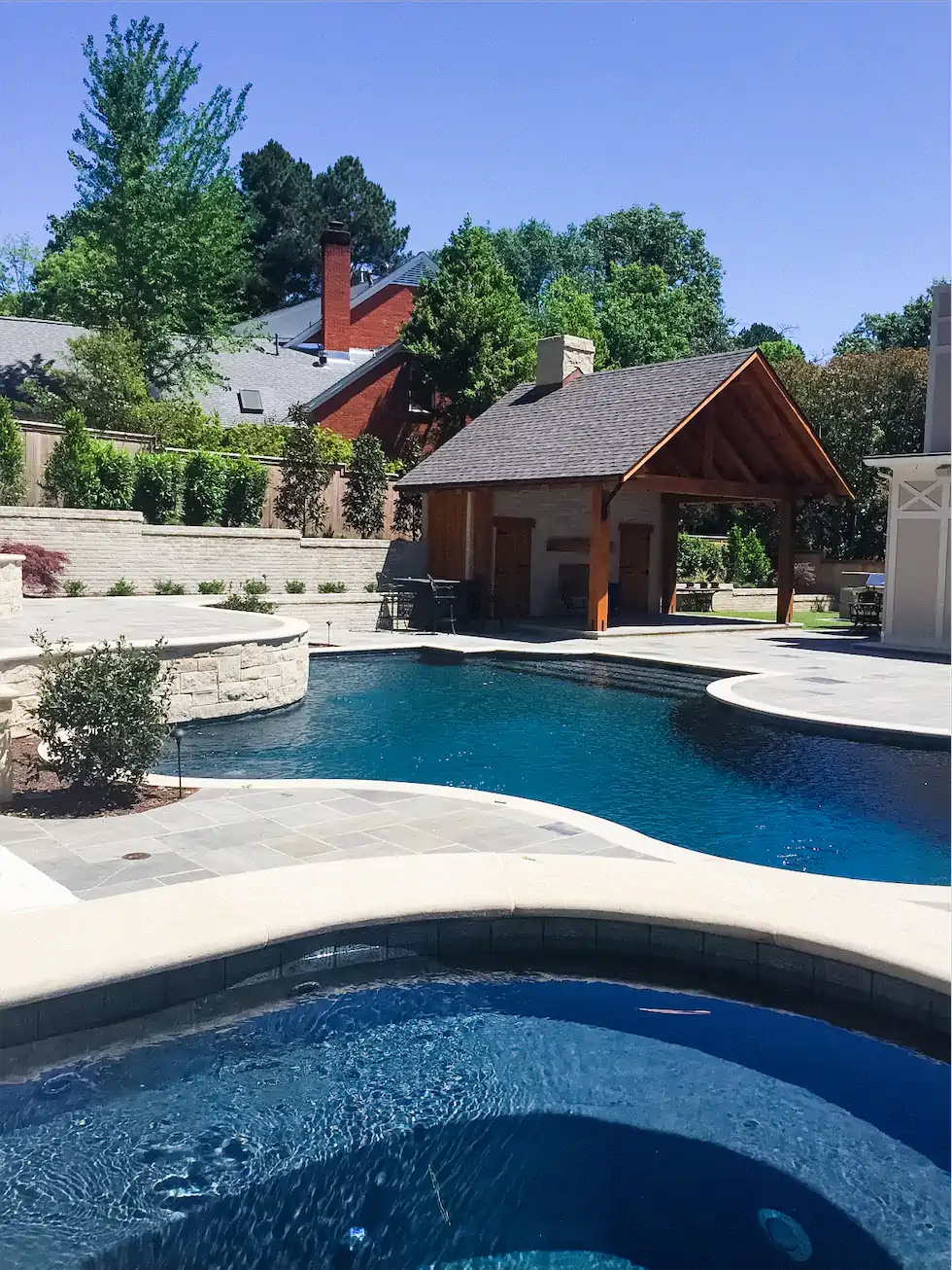 custom gunite hot tub, custom gunite swimming pool, and outdoor living space with large pergola and outdoor kitchen and fire pit by Ogden Pools in Memphis, TN